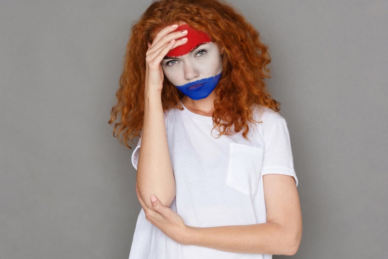 Face of young sad woman painted with flag of Holland