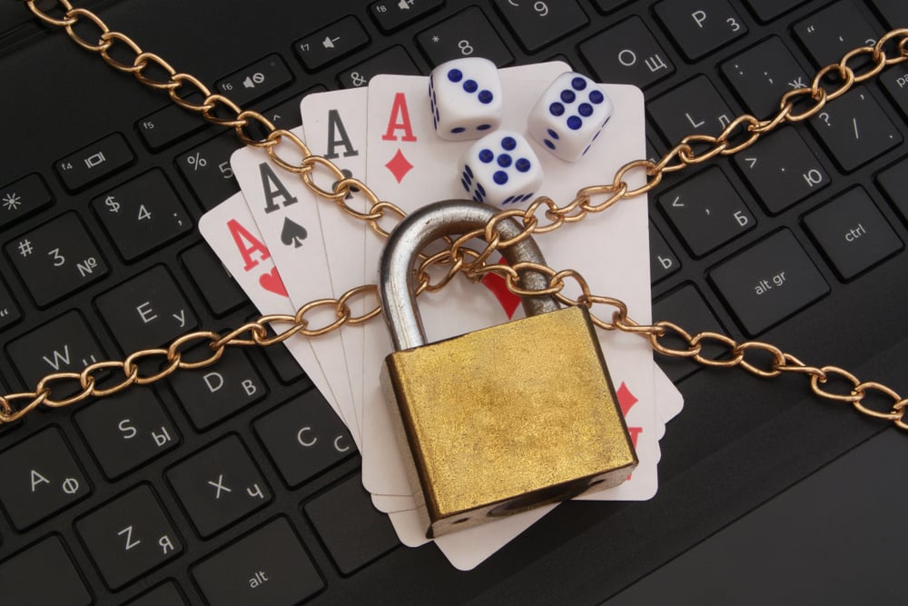 playing cards and dice lying on laptop keyboard held by lock and chains