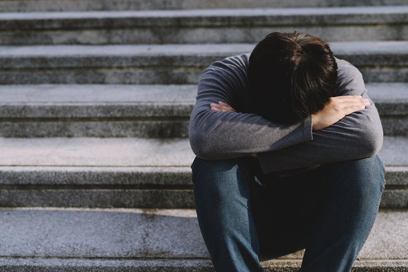 unemployed male looking upset on steps