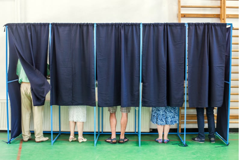 People behind the curtains of a voting booth