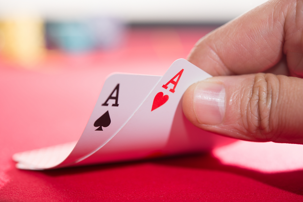 poker player lifts two Ace cards