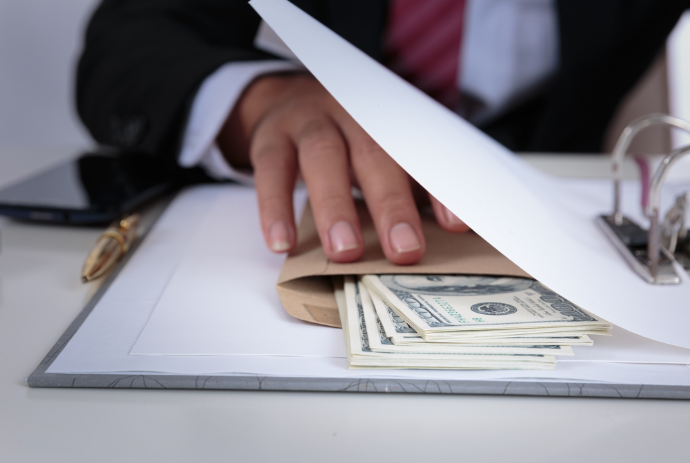 Businessman holds money in envelope between documents