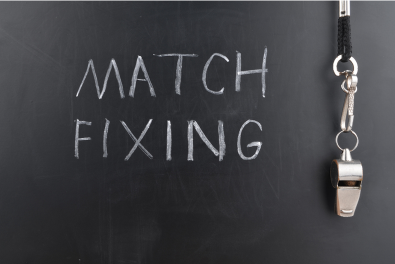 Match-fixing written on a blackboard beside a whistle